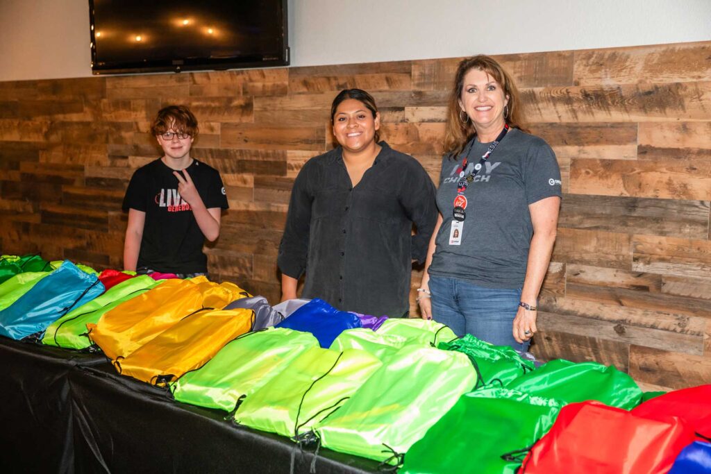 Volunteers standing behind a table with colorful bags during a Hope For Kids event.